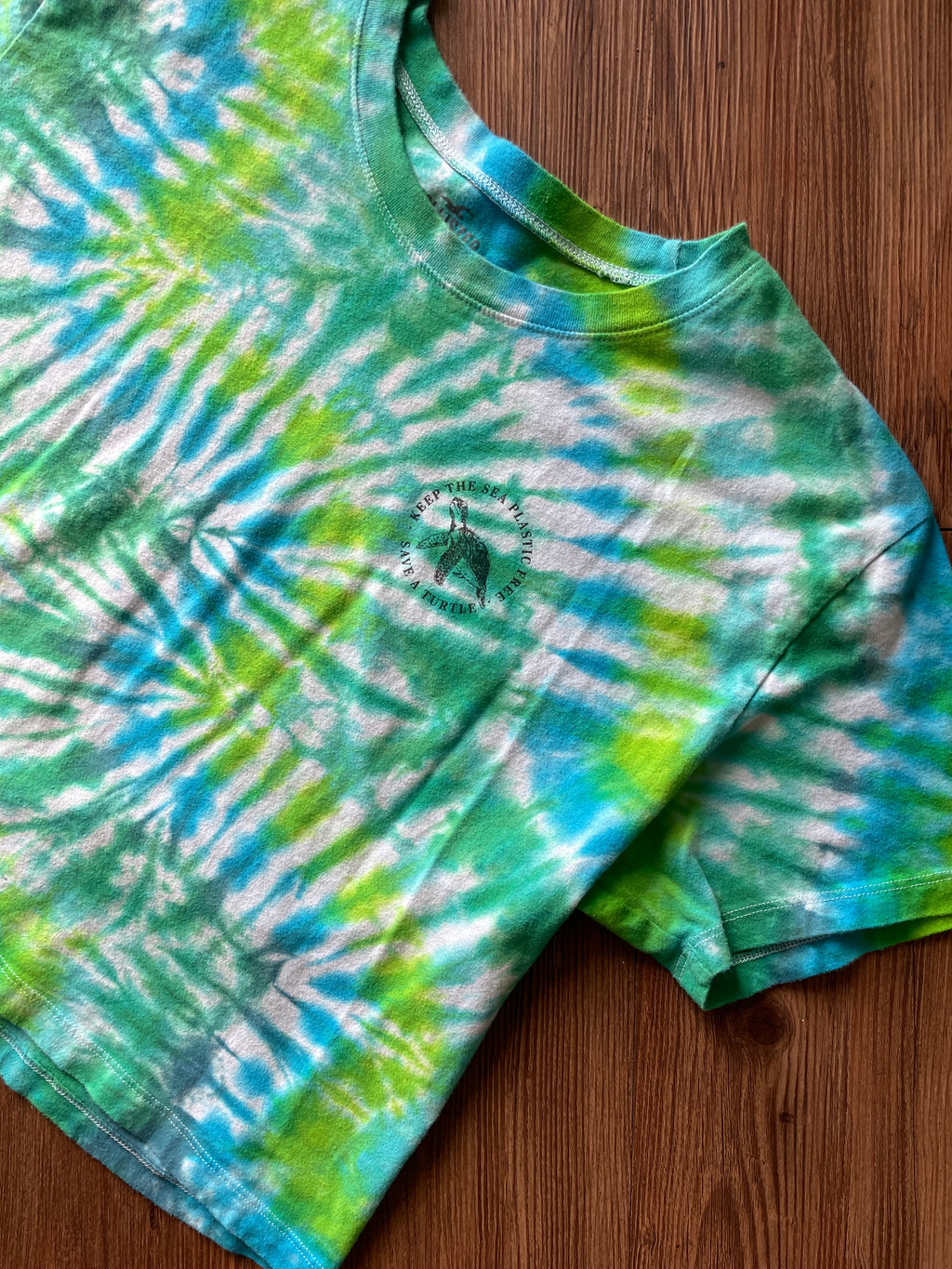 LARGE Women’s/SMALL Men's Keep the Sea Plastic Free Tie Dye Crop Top | Shades of Green and Blue Pleated Tie Dye Short Sleeve Top