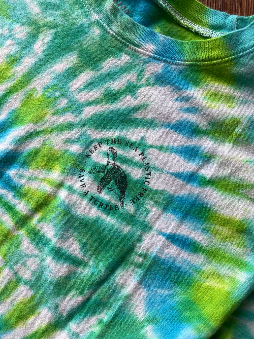 LARGE Women’s/SMALL Men's Keep the Sea Plastic Free Tie Dye Crop Top | Shades of Green and Blue Pleated Tie Dye Short Sleeve Top